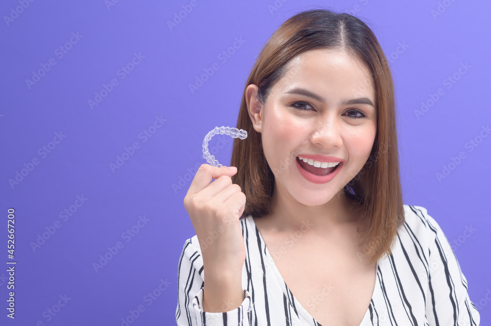 Young smiling woman holding invisalign braces in studio, dental healthcare and Orthodontic concept.. Young smiling woman holding invisalign braces in studio, dental healthcare and Orthodontic concept..