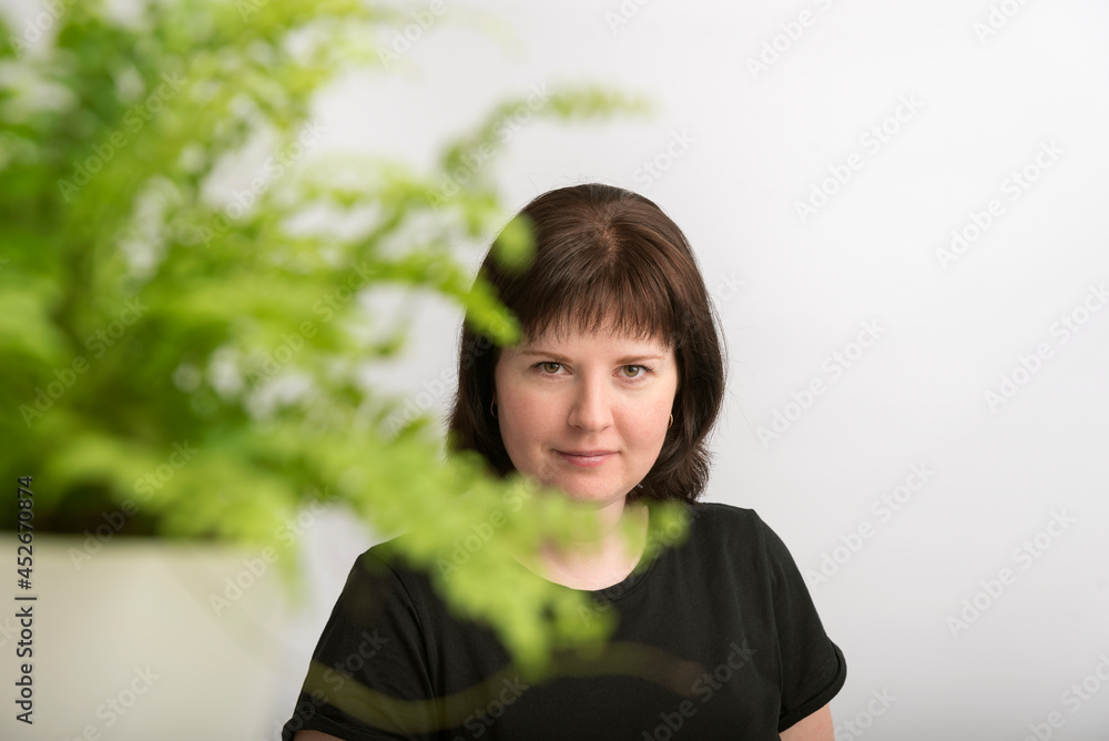 Portrait of beautiful young woman with natural dark hair in isolation on white background with bright green flower. Portrait of beautiful young woman with natural dark hair in isolation on white background with bright green flower.