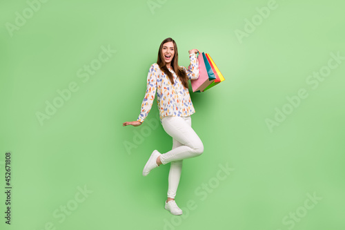Full size photo of crazy brunette hairdo young lady with bags wear blouse trousers sneakers isolated on green background