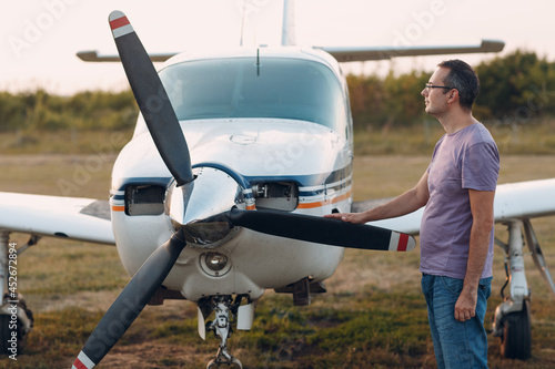 Pilot man standing next to a small private airplane