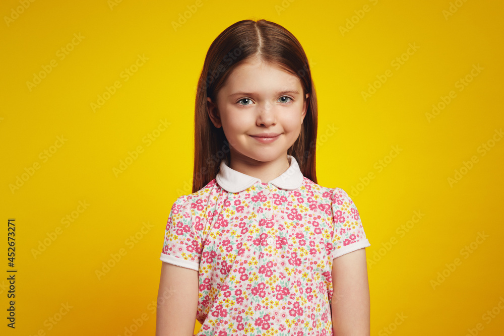 Portrait of adorable schoolgirl in casual summer clothes, looking at camera with happy expression, isolated over yellow background Portrait of adorable schoolgirl in casual summer clothes, looking at camera with happy expression, isolated over yellow background