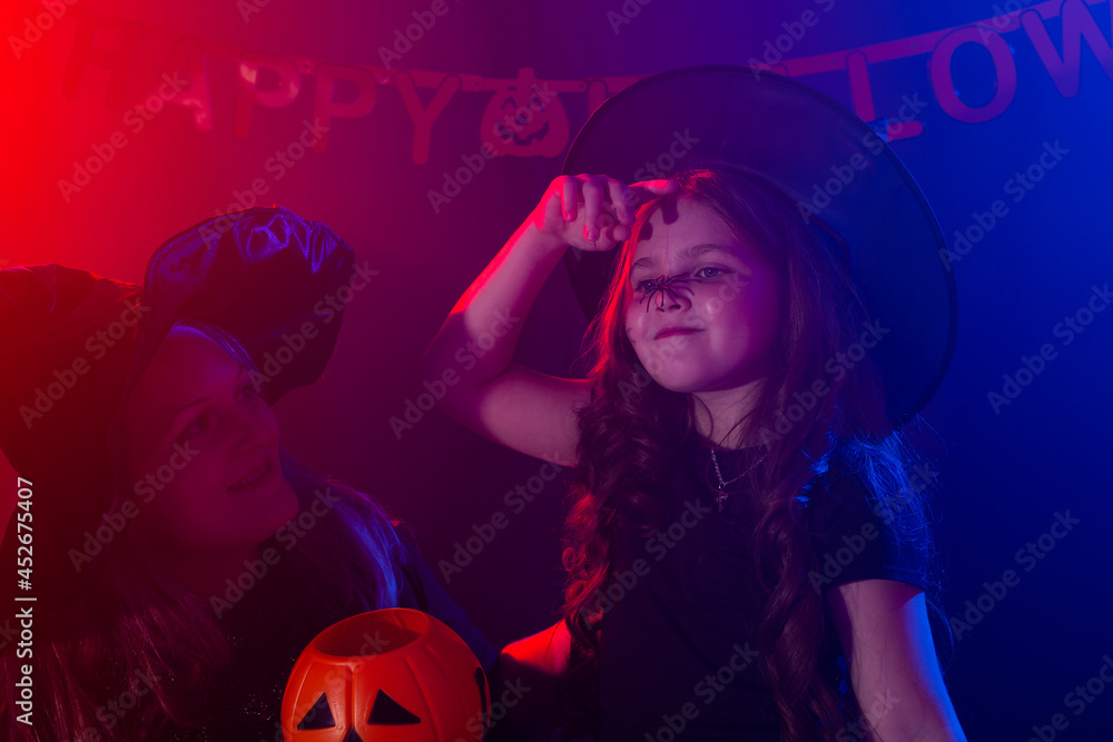 Fototapeta premium Funny child girl and woman in witches costumes for Halloween with pumpkin Jack.