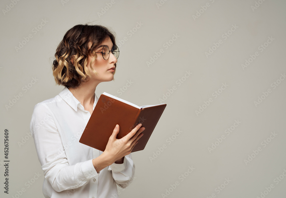 woman with curly hair in glasses with a book in her hands work by Studio