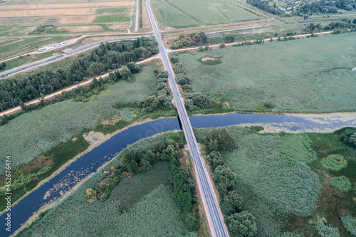 Automobile asphaot village road crosses the river across the bridge in the village, shot from above