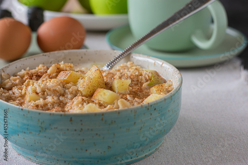 Porridge with apples and cinnamon in a bowl on kitchen table