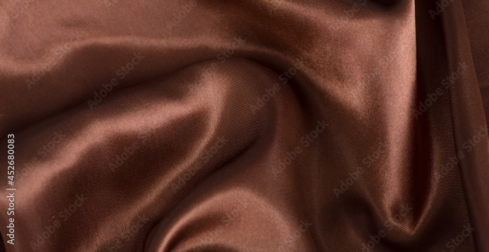 Fototapeta premium brown or chocolate silk satin fabric texture background.Cloth soft wave. Creases of satin
