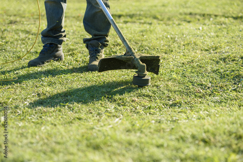 A man mows the grass on the front lawn with a mower