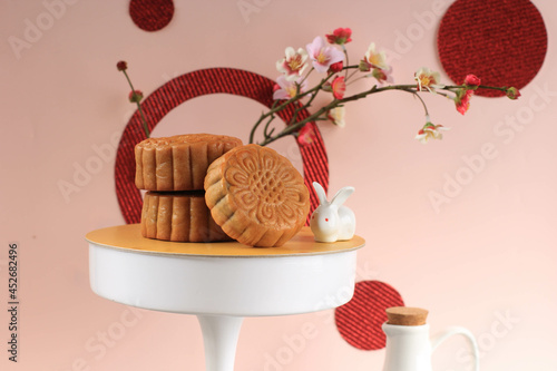 Mooncake on Light Pink Background with Pink Flower. Concept Moon Cake on Mid Autumn Festival. Mooncake Popular as Kue Bulan. photo
