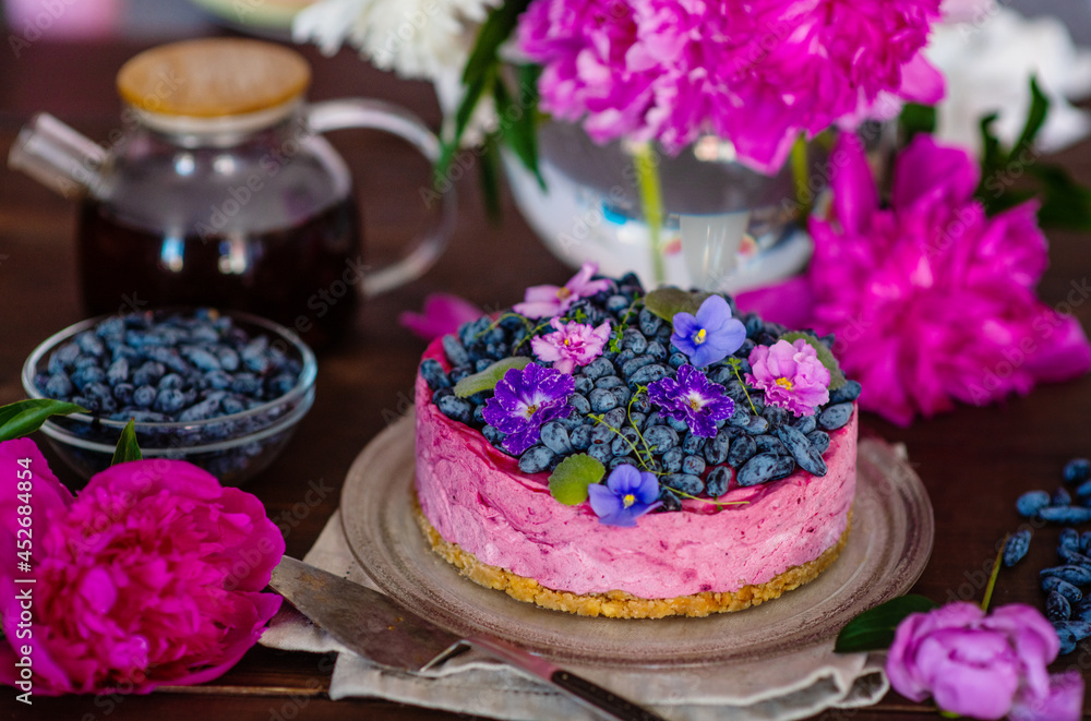Purple cheesecake with honeysuckle, violet flowers and a background of peonies and a whole cake Purple cheesecake with honeysuckle, violet flowers and a background of peonies and a whole cake