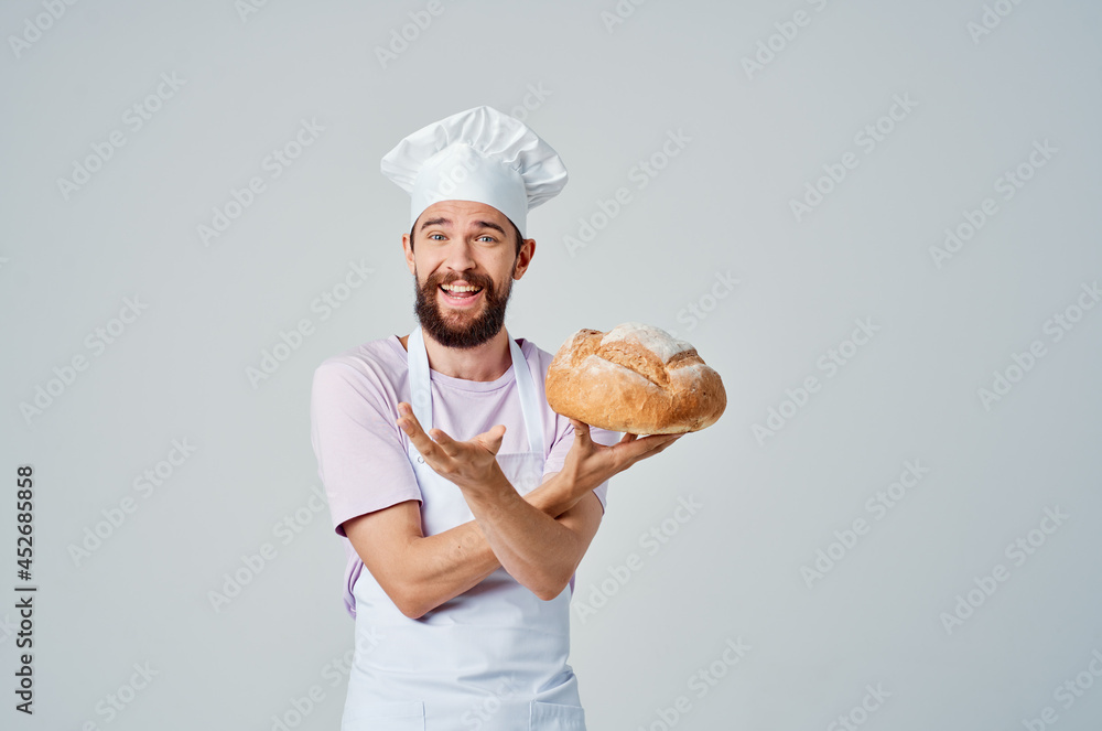 emotional Baker in a White apron with bread in his hands Professional emotional Baker in a White apron with bread in his hands Professional