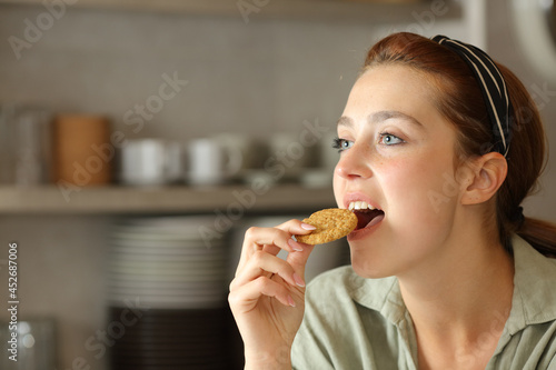Woman eating cookie in the kitchen at home