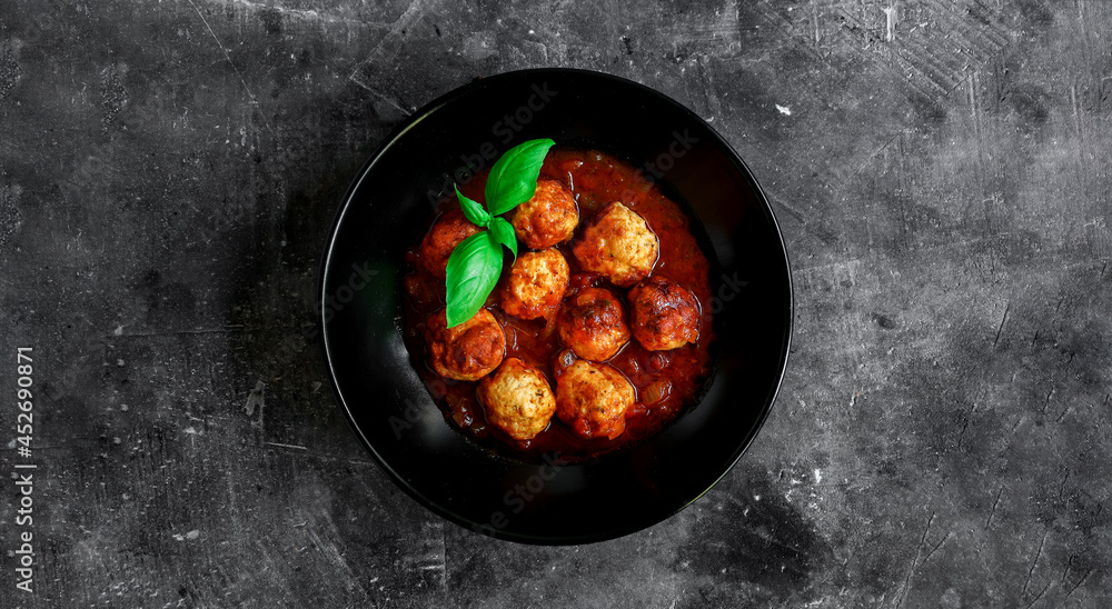 Chicken meatballs with basil and tomato sauce. Dark background. Copyspace. Meatballs with tomato and chili. Isolated. Top view