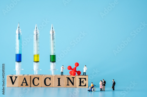 miniature of doctor and patient wear a mask to prevent virus..red virus with Wooden cubes with words ''vaccine" and syringe.