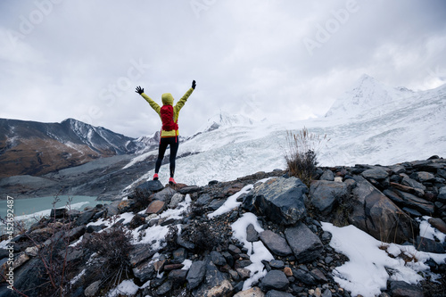 Successful woman trail runner open arms to winter fossil glacier snow mountains