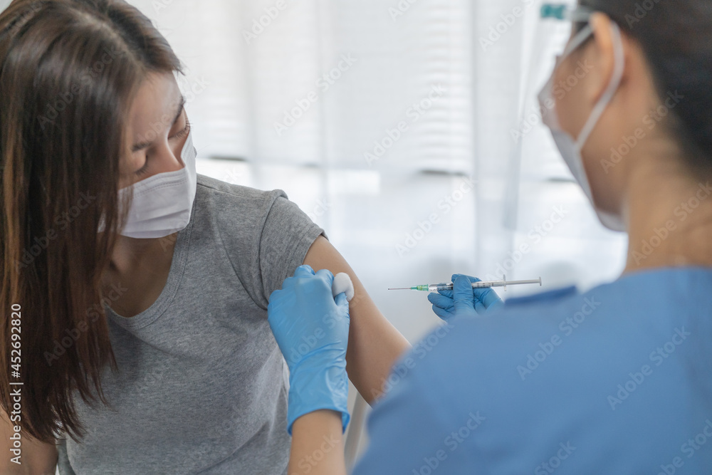 Covid-19,coronavirus hand of young woman nurse,doctor giving syringe vaccine, inject shot to asian arm's patient. Vaccination, immunization or disease prevention against flu or virus pandemic concept. Covid-19,coronavirus hand of young woman nurse,doctor giving syringe vaccine, inject shot to asian arm's patient. Vaccination, immunization or disease prevention against flu or virus pandemic concept.
