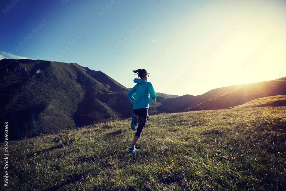 Fototapeta premium Young woman runner running at mountain top