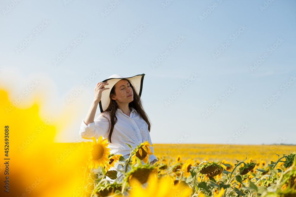 woman in a hat in a field of sunflowers woman in a hat in a field of sunflowers