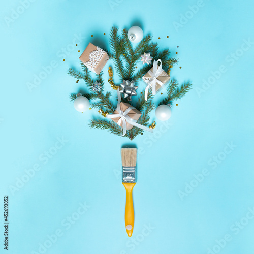 Creative composition Christmas and New year. Paint brush with Christmas fir and ornaments on a red background. Minimal New Year background decoration concept.