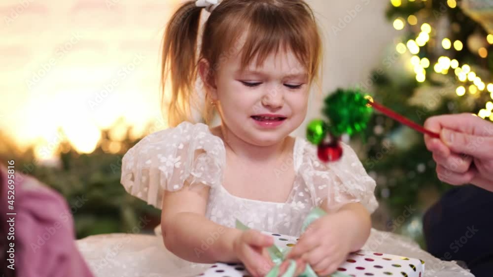 a little girl packs a gift at the Christmas tree. a little girl packs a gift at the Christmas tree.