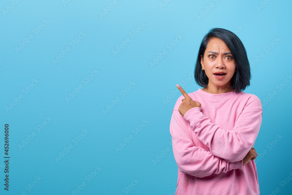 Attractive asian woman shocked and pointing finger to empty space Attractive asian woman shocked and pointing finger to empty space