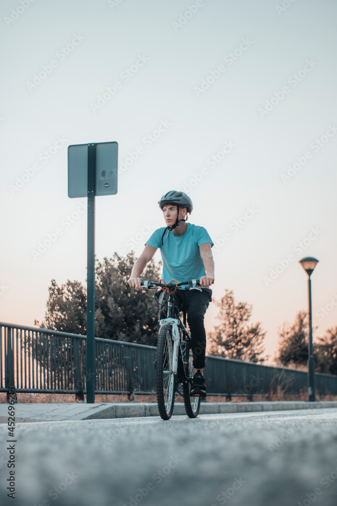 Adolescente de ruta haciendo ciclismo en la carretera de la ciudad junto a la puesta de sol