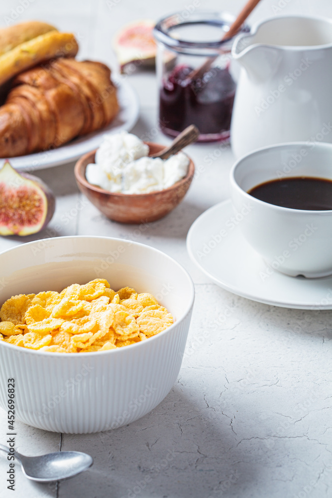 Breakfast table with cornflakes, croissants and cup of coffee. Gray tile background, copy space. Breakfast table with cornflakes, croissants and cup of coffee. Gray tile background, copy space.