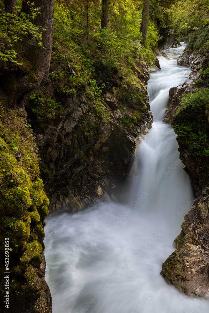 A mountain creek is flowing among moss covered rocks and trees and into a waterfall A mountain creek is flowing among moss covered rocks and trees and into a waterfall