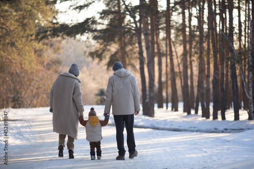 family dad mom and baby walk in a pine park forest in winter