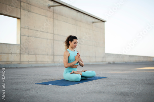 Young woman practising yoga outdoors. Beautiful girl stretching outside.