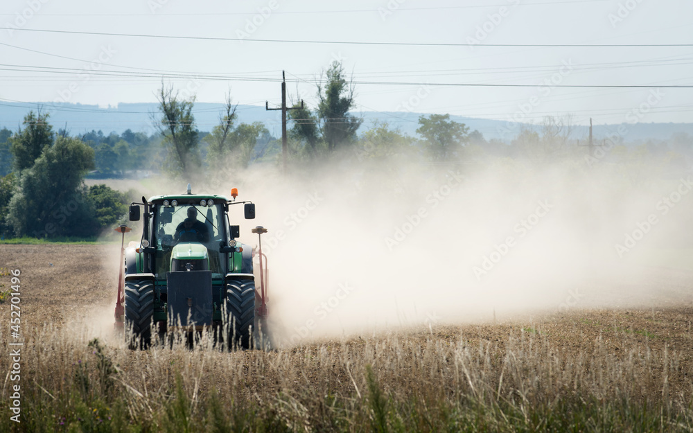 Fototapeta premium Tractor plowing dry farm land at autumn