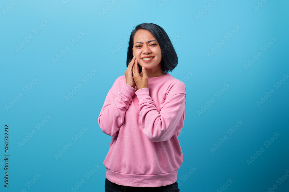 Portrait of young Asian woman touching cheek while suffering from terrible toothache Portrait of young Asian woman touching cheek while suffering from terrible toothache