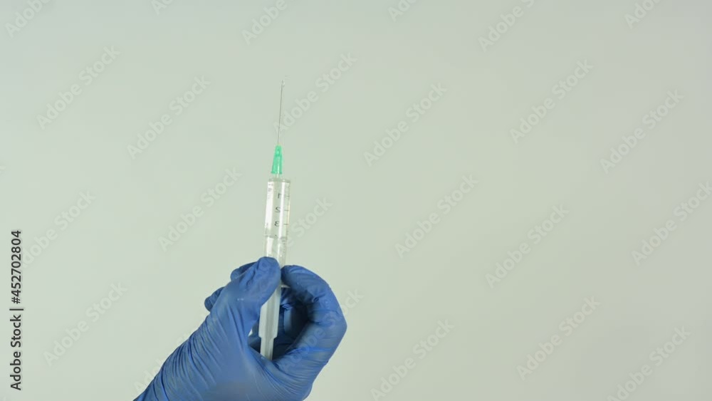 man's hand, with blue latex gloves, extracting liquid from bottles with liquid with a syringe man's hand, with blue latex gloves, extracting liquid from bottles with liquid with a syringe