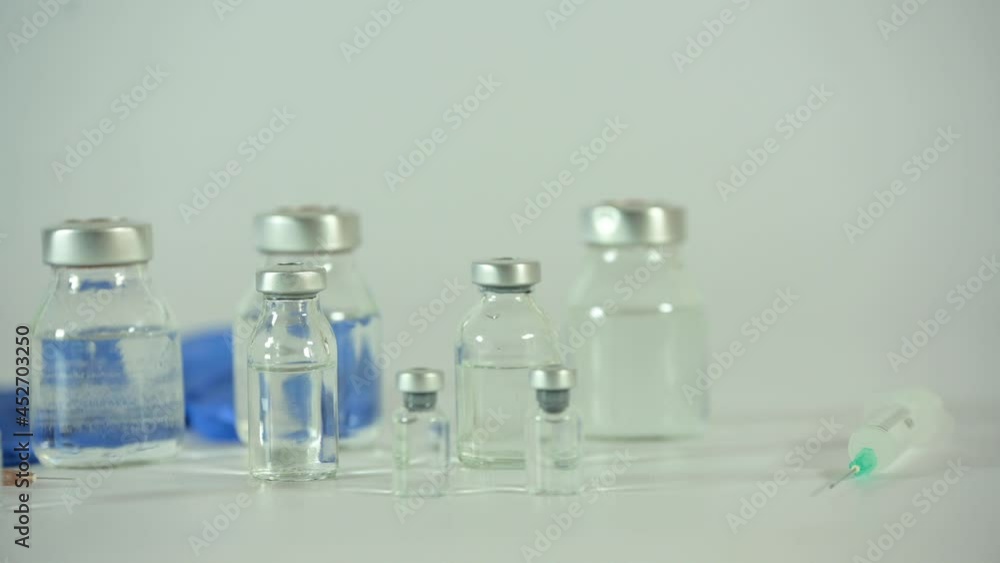 glass bottles for covid-19 and other vaccines with different size syringes and blue latex gloves with camera movement glass bottles for covid-19 and other vaccines with different size syringes and blue latex gloves with camera movement