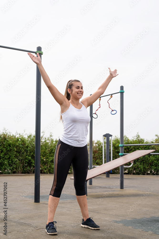 Happy woman working out on the sports ground in sunny summer day