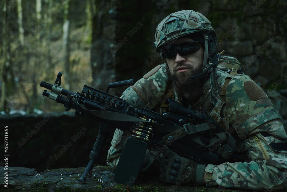 Portrait of airsoft player in professional equipment with machine gun in the forest. Soldier with weapons at war Portrait of airsoft player in professional equipment with machine gun in the forest. Soldier with weapons at war