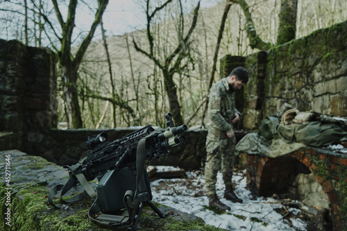 Portrait of airsoft player in professional equipment with machine gun in the forest. Soldier with weapons at war