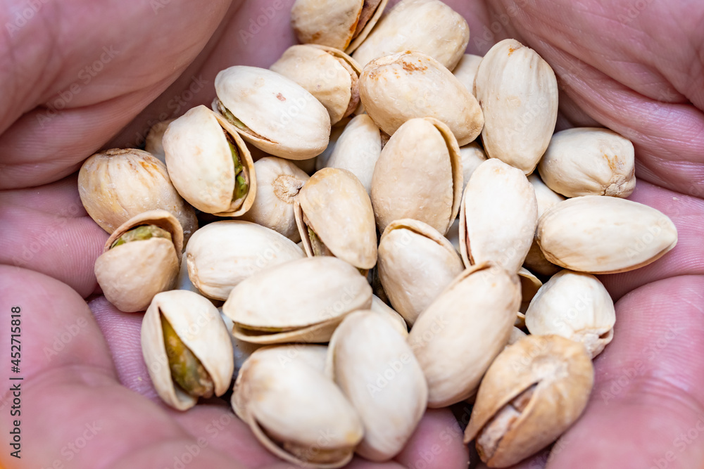 Hands of a person with a handful of pistachios. Nuts source of fiber. concept of care, food and healthy lifestyle