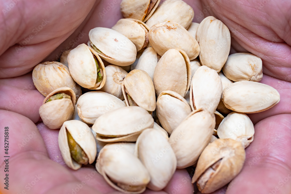 Hands of a person with a handful of pistachios. Nuts source of fiber. concept of care, food and healthy lifestyle Hands of a person with a handful of pistachios. Nuts source of fiber. concept of care, food and healthy lifestyle