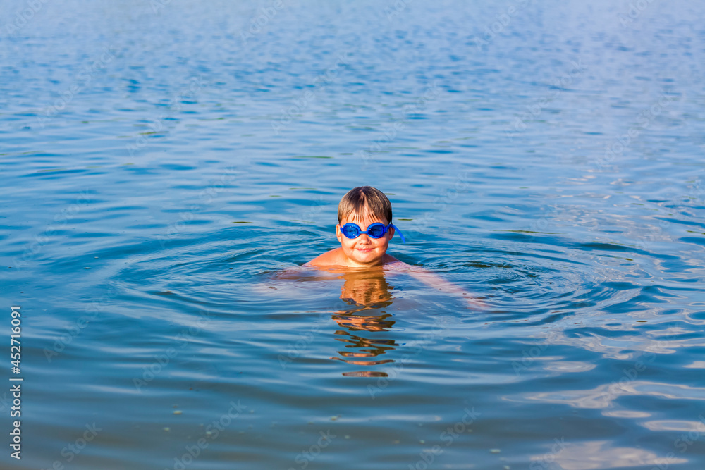 A happy child is swimming in the river on a very hot summer day. Swim in reservoirs. A happy family has fun and splashes in the water in the summer.