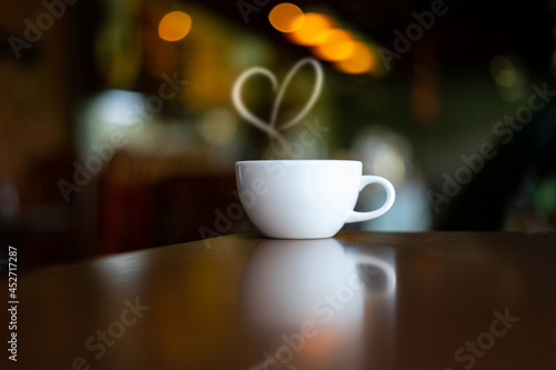 White Hot coffee cup of love on Wood Table in blurred Coffee Shop background.Photo with soft focus.