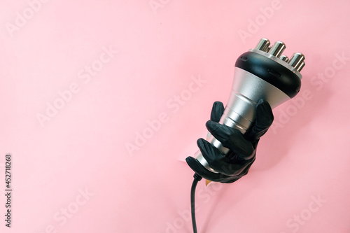 RF lifting hardware massage on a pink background. hand in a black glove with an apparatus. photo