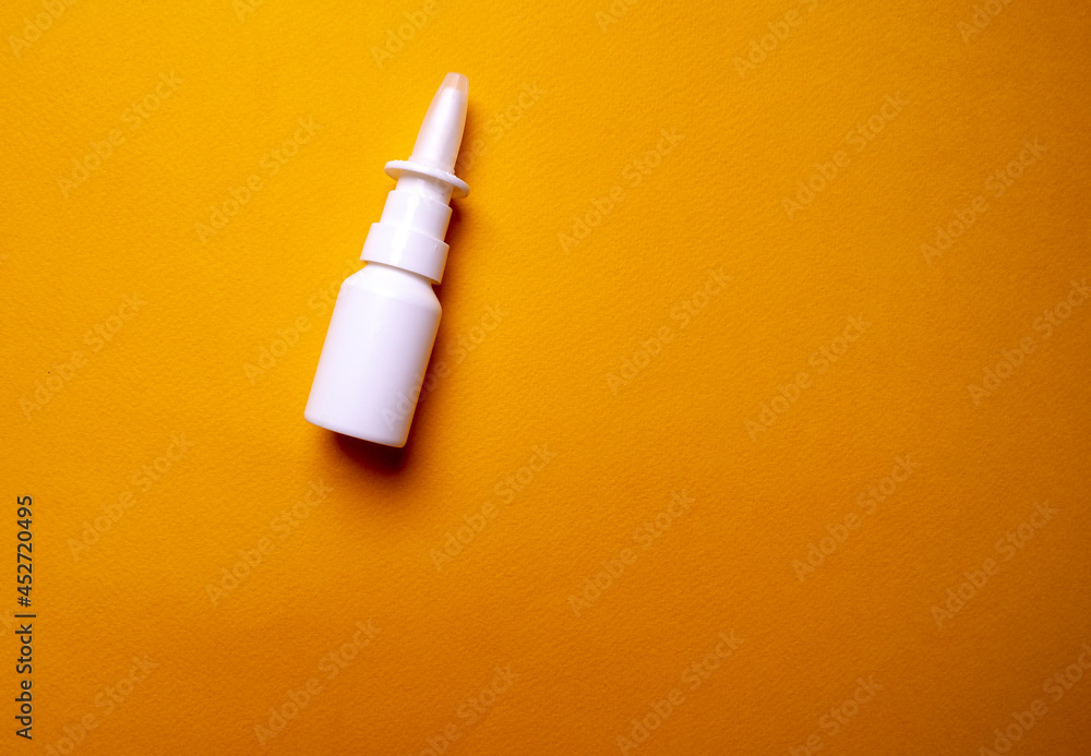 Bottle of nose drops on a yellow background close-up. Spray for the nose. View from above Bottle of nose drops on a yellow background close-up. Spray for the nose. View from above
