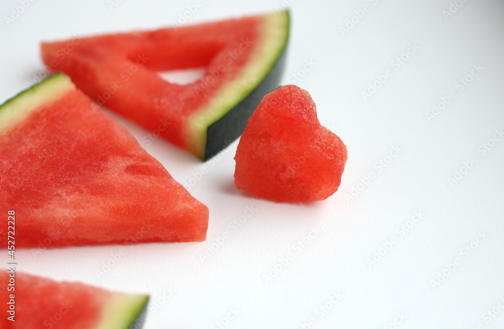 Triangular pieces of watermelon with a heart, cut from the pulp of a watermelon on a light background, red watermelon Triangular pieces of watermelon with a heart, cut from the pulp of a watermelon on a light background, red watermelon