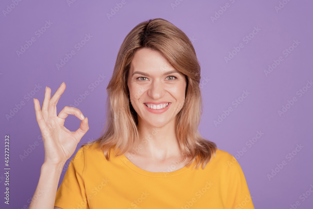 Photo of young cheerful woman happy positive smile show okay alright sign deal done cool isolated over violet color background Photo of young cheerful woman happy positive smile show okay alright sign deal done cool isolated over violet color background