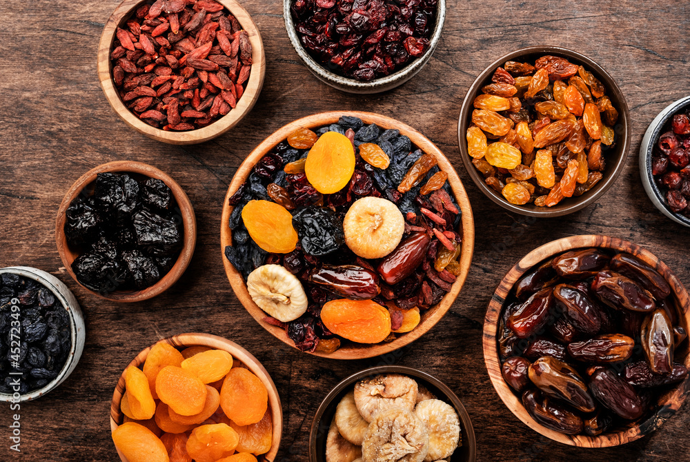 Dried fruits bowl. Healthy food snack: sun dried organic mix of apricots, figs, raisins, dates and other on wooden table, top view Dried fruits bowl. Healthy food snack: sun dried organic mix of apricots, figs, raisins, dates and other on wooden table, top view