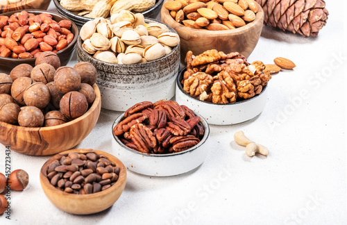 Nuts in bowls. Almonds, hazelnuts, walnuts and other. Healthy food snack mix on white table, top view, copy space