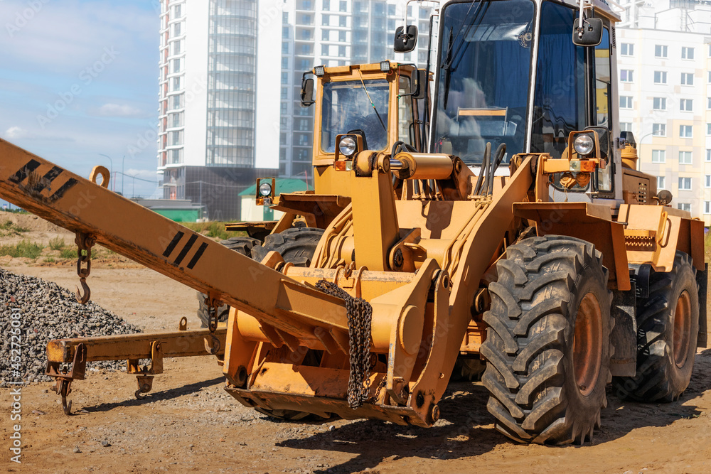 Powerful wheel loader for transporting bulky goods at the construction site of a modern residential area. Construction equipment for lifting and moving loads.