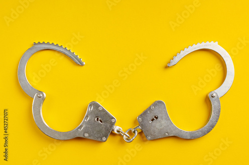 Tableau sur toile Opened handcuffs on yellow background.