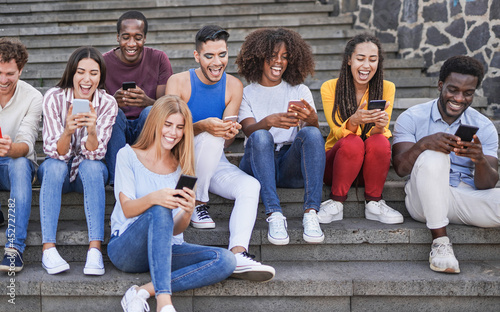 Group of young diverse friends using mobile phone in the city - Multiracial people having social moment and enjoy technology 