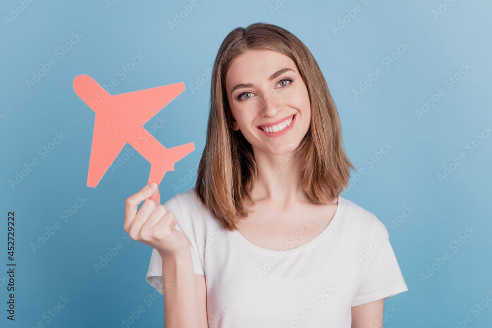 Portrait of lovely pretty cute lady hold paper plane figure toothy beaming smile on blue background Portrait of lovely pretty cute lady hold paper plane figure toothy beaming smile on blue background
